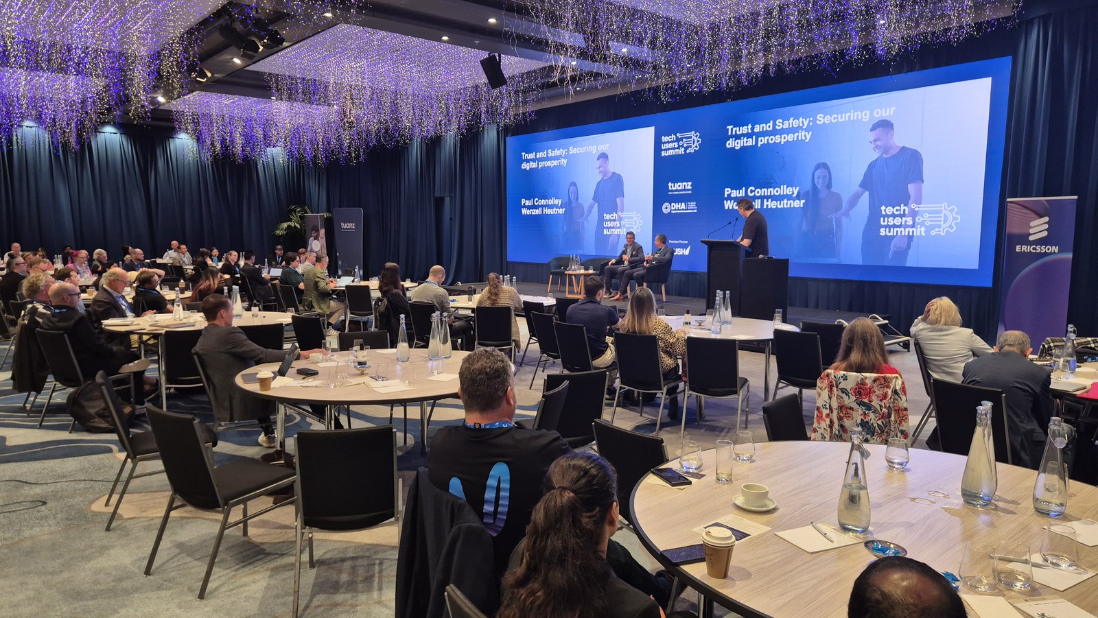 The Tech Users Summit room during the Trust and Safety session, with delegates at round tables facing the stage